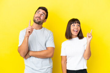 Young couple isolated on yellow background pointing a great idea and looking up