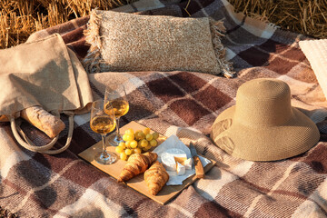 Romantic picnic with glasses of wine and croissants on wheat field