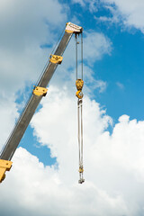 Crane boom with construction hook on sky background