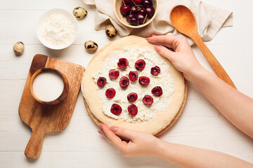 Woman cooking tasty khachapuri on light wooden background