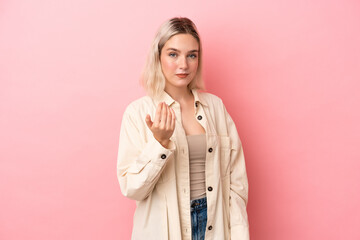 Young caucasian woman isolated on pink background inviting to come with hand. Happy that you came