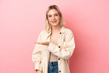 Young caucasian woman isolated on pink background presenting an idea while looking smiling towards