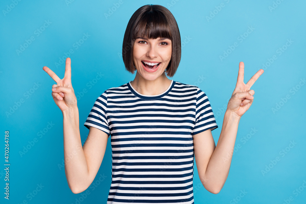 Sticker Photo of cute brunette young lady show v-sign wear striped t-shirt isolated on blue background