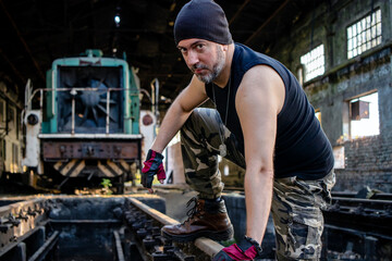Man climbing on the rail track in front of a locomotive in an abandoned marshalling yard. Exercising parkour.  