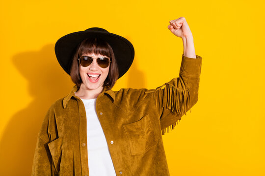 Photo of sweet charming lady wear cowgirl outfit dark glasses headwear rising fist showing biceps isolated yellow color background