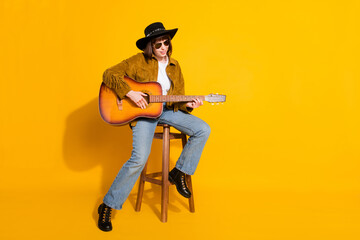 Naklejka premium Photo of pretty adorable lady wear cowgirl outfit glasses headwear playing guitar singing empty space isolated yellow color background