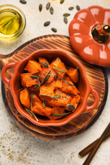 Pot with tasty roasted pumpkin on light background