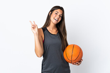 Young brazilian woman playing basketball isolated on white background smiling and showing victory sign