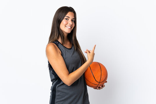 Young brazilian woman playing basketball isolated on white background pointing finger to the side