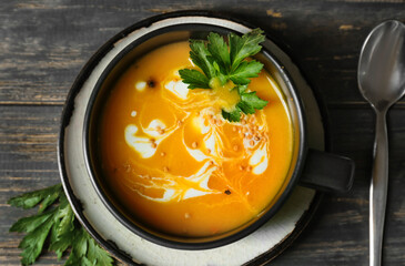 Cup with delicious pumpkin cream soup on wooden background, closeup