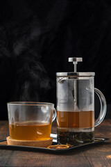 Hot winter tea served with a french press on a wooden floor.