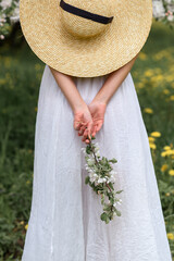 beautiful caucasian girl in a blooming garden in a red T-shirt and a long skirt with a hat