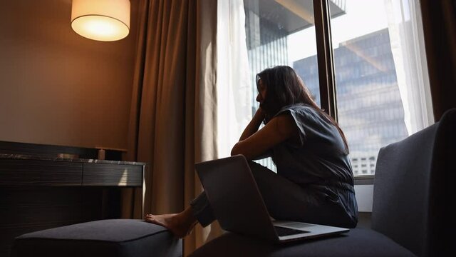 Silhouette attractive asian womanWorking from home bored alone with laptop. Procrastination, tired Asian young woman to do remote work online on computer in living room. Confinement from coronavirus.