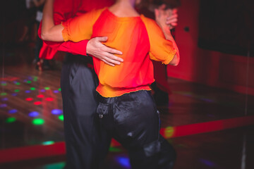 Obraz na płótnie Canvas Couples dancing traditional latin argentinian dance milonga in the ballroom, tango salsa bachata kizomba lesson in the red lights, dance festival