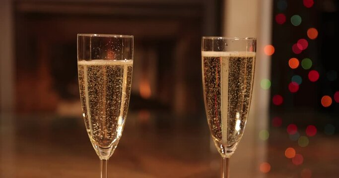 Closeup of two glasses of fizzy champagne in front of burning fireplace, Relaxation by the fireplace