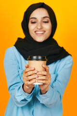 cheerful woman a glass of coffee in hands near the face yellow background