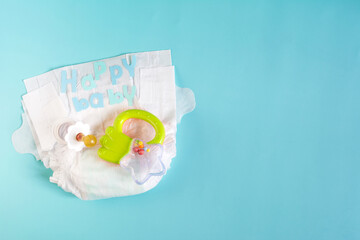 Flatley is a set of children's things on a colored background of copy space. Baby diapers, pacifier on a light background and the inscription "happy baby"