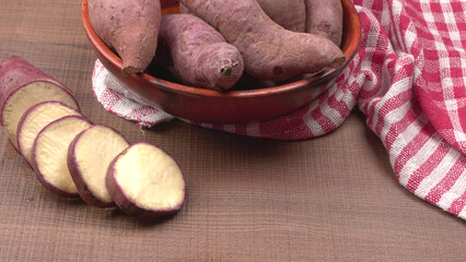 slices of sweet potatoes on wooden background, close up. Raw sweet potatoes or batatas.