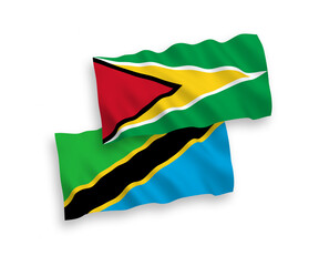 National vector fabric wave flags of Co-operative Republic of Guyana and Tanzania isolated on white background. 1 to 2 proportion.