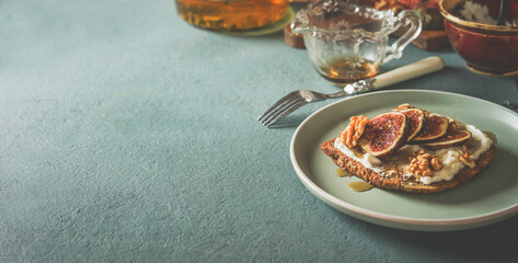 Breakfast background with french toast with creme cheese, figs and honey on plate with kitchen...