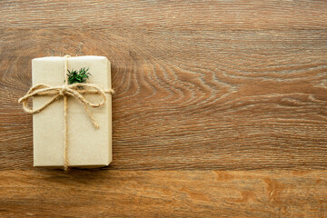 Brown gift box with festive decoration for Christmas and new year is on wood background. Top view with copy space, flat lay.