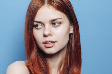 Naklejka premium attractive woman with bare shoulders red hair close-up blue background