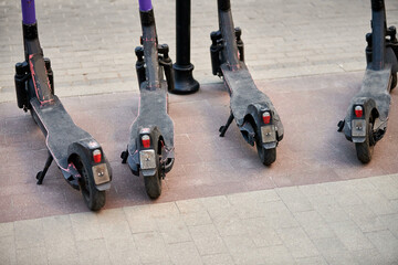 Motorized scooter parking for hourly rent on sidewalk street, vehicle for fast movement around town