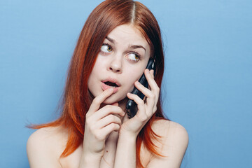 woman with red hair bare shoulders talking on the phone