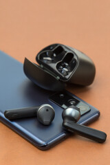 Wireless headphones are the phone screen on a brown background, the concept of a new purchase.