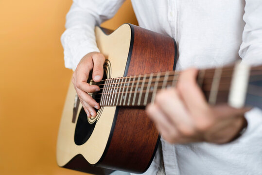 Young man playing guitar, close up, focus on hand and strings. The boy graduated from school music a long time ago and has not played, and now he is learning to play again with a new passion