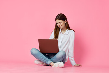 Naklejka premium woman sitting on floor with laptop online shopping shopping technology pink background
