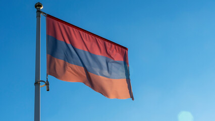 Variant of the flag of Armenia with alternative colors on the flagpole waving in the wind on a blue background.
