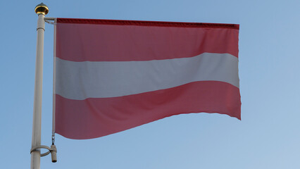 National flag of Austria on a flagpole in front of blue sky with sun rays and lens flare. Diplomacy concept.