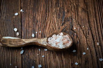 Pink himalayan salt on an ceramic spoon over wooden backround