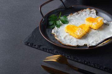 Homemade fried egg in a vintage pan a grey background. Heart-shaped yolk. Copy space for text