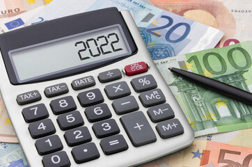 Calculator with money and a pen - 2022