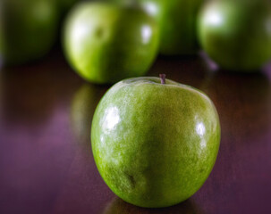 Single green apple in the foreground from the bunch.