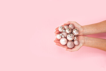 In women's palms, decorative pink shiny balls on a pink background. Top view, flat lay.