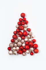 Decorative balls are laid out in the form of a Christmas tree on a white background. Top view, flat lay.
