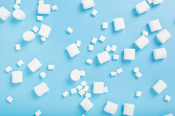 Fototapeta na wymiar White marshmallows on a blue background. Top view, flat lay.