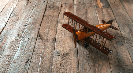 Wooden retro toy airplane on the wooden background with copy space.