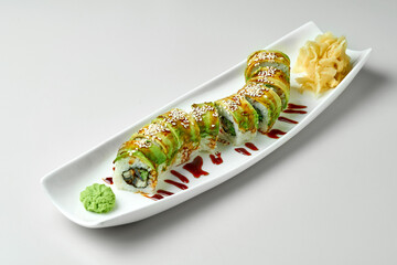 Roll green dragon with avocado and eel in a white plate on a gray background