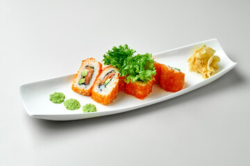 California sushi roll with salmon and avocado in a white plate on a gray background