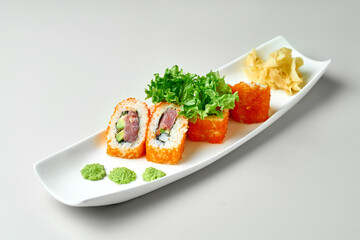 California sushi roll with tuna and avocado in white plate on gray background