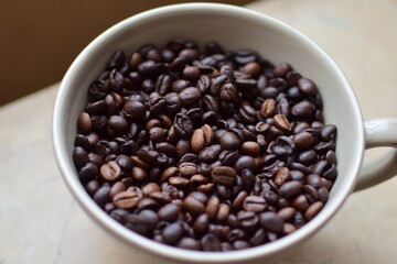 Roasted coffee beans in a cup as a close up