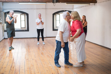 Kissing Caucasian retired couple in dance studio. Happy old partners wearing glasses smooching after dancing. Dance, hobby, healthy lifestyle concept