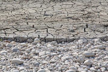 Dry sediments, land and pebbles after desludging of a lake in order to purge water and protect fauna and flora-nature protection context,ecology or global warming concept, texture, natural background