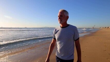 64 year old man walking at the beach near sunset.
