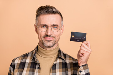 Photo of mature man hold bank card income cashless advertise recommend isolated over beige color background