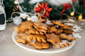 Partially blurred plate of gingerbread cookies in shape of christmas trees, stars and hearts on kitchen countertop